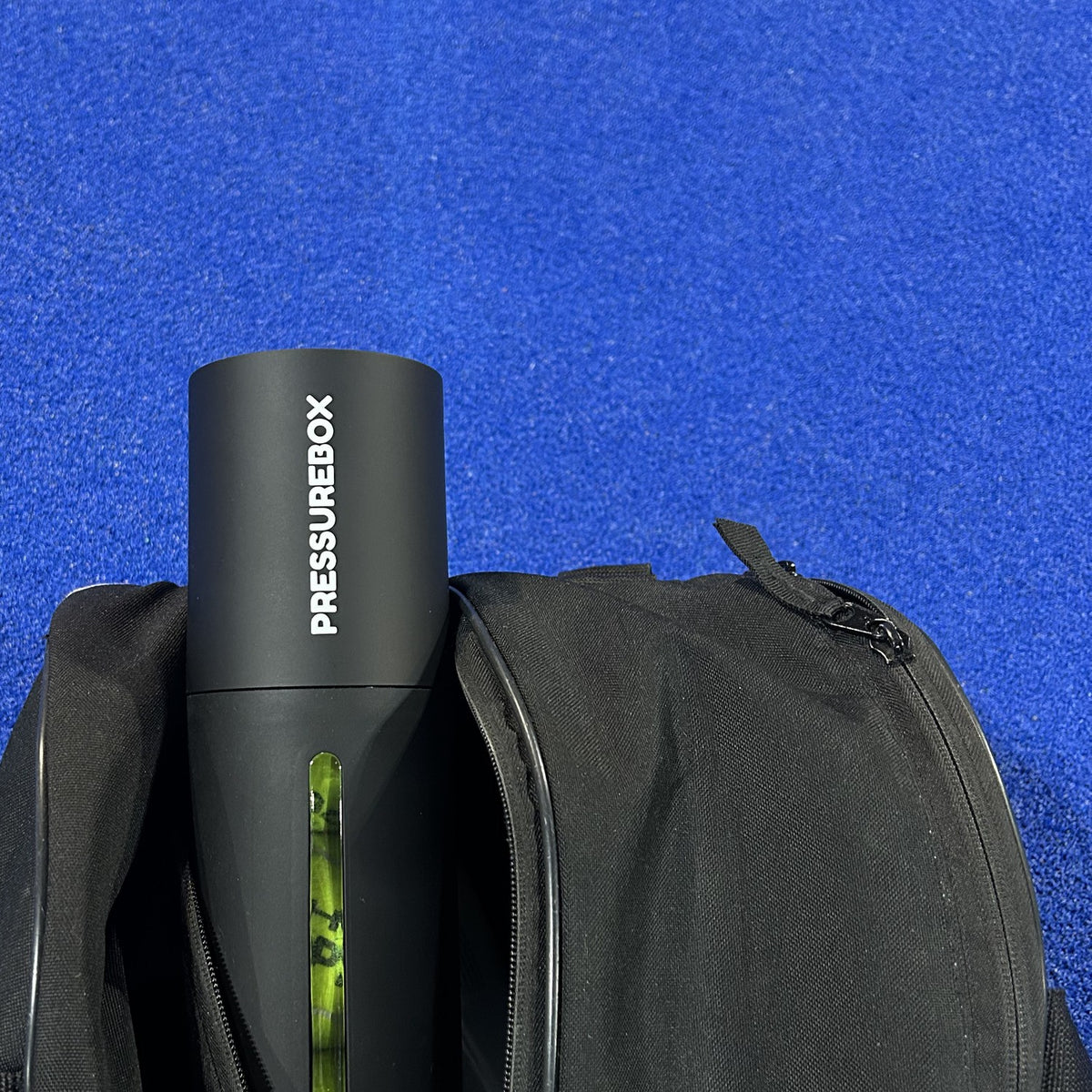 Pressurebox Pro Padel ball pressurizer packed in a padel bag on a blue padel court